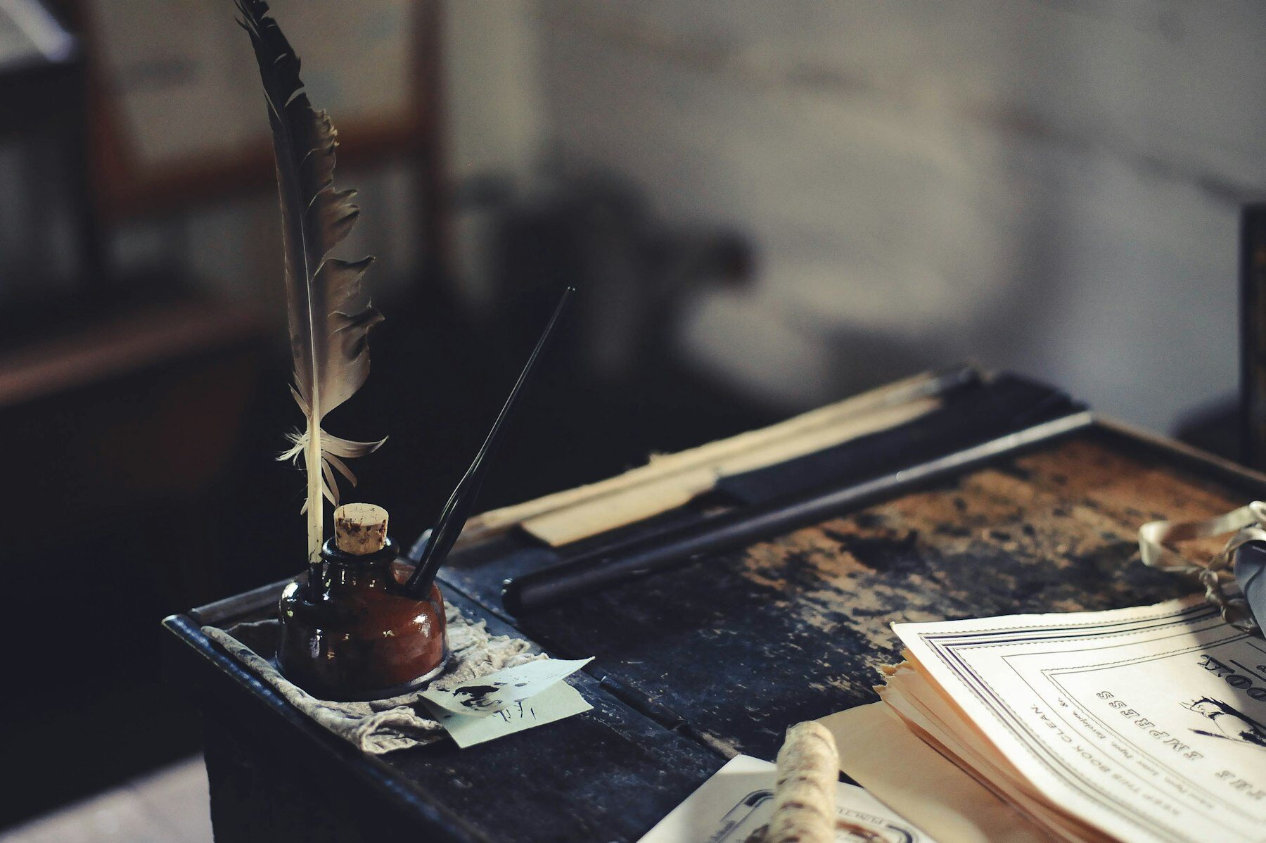 A quill pen in an inkwell on an old writing desk, letters stacked beside it